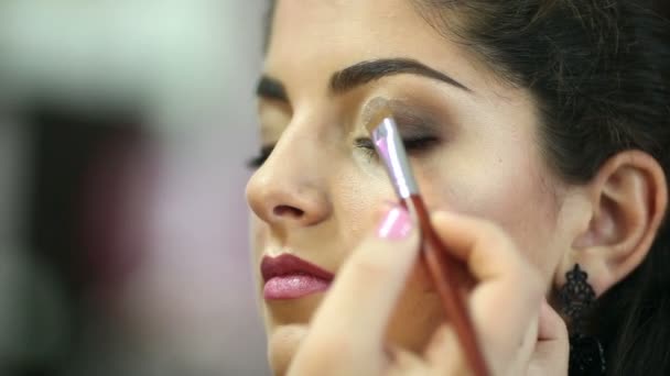 Una mujer guapa con maquillaje aplicado por un maquillador . — Vídeo de stock