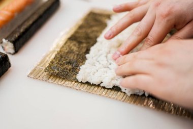 Şef rulo California yapıyor. Şefin elleri Nori 'nin üzerine.