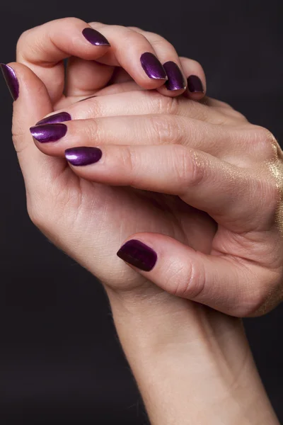 Close-up van gekruiste vrouwelijke handen versierd met paarse vingernagel verf — Stockfoto