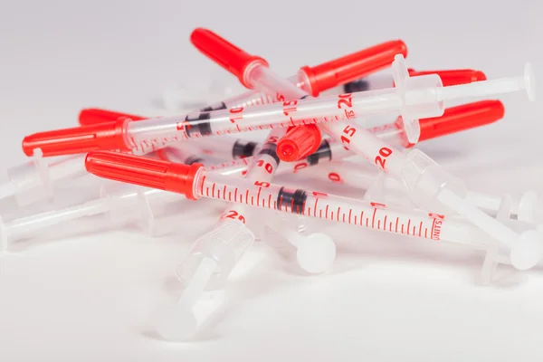 Pilha de seringas vazias com tampas de segurança vermelhas — Fotografia de Stock
