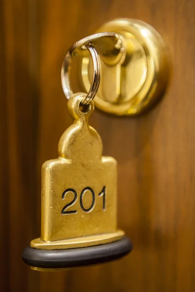 Llave de la habitación de hotel acostado en la cama con llavero — Foto de Stock