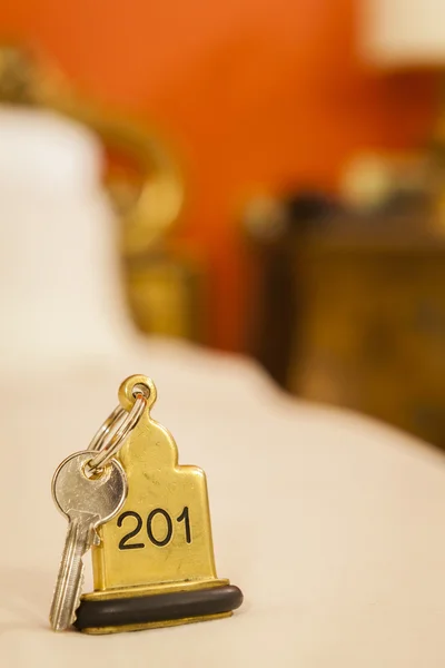 Llave de la habitación de hotel acostado en la cama con llavero — Foto de Stock