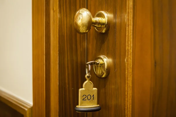 Chave da sala de hotel deitada na cama com chaveiro Fotografia De Stock