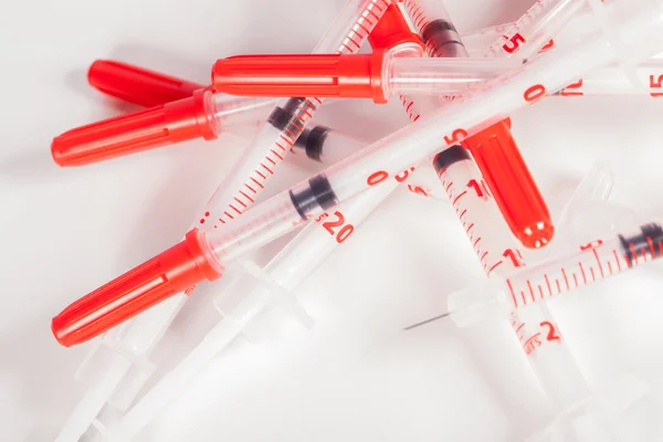Pilha de seringas vazias com tampas de segurança vermelhas — Fotografia de Stock