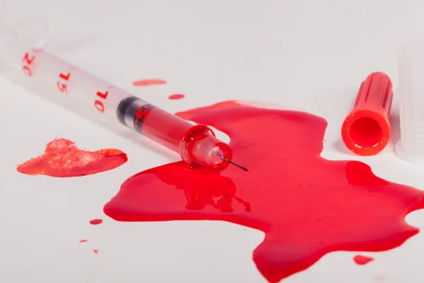 Seringa esguichando sangue vermelho em fundo branco — Fotografia de Stock