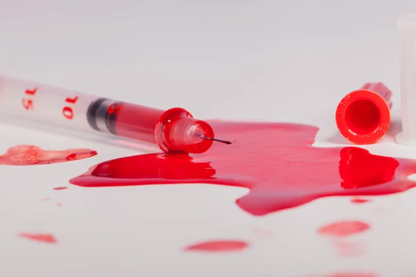 Seringa esguichando sangue vermelho em fundo branco — Fotografia de Stock
