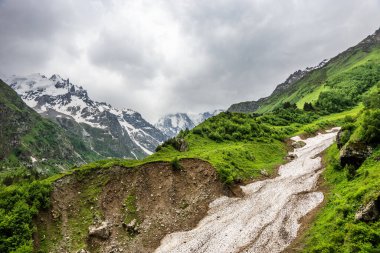 Bulutlu bir yaz gününde Alp Çayırı 'ndaki çığ yolu. Kafkasya dağları Elbrus yakınlarında, Rusya.