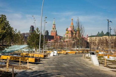 Zaryadye Park manzarası ilkbaharın başlarında güneşli bir gün: Moskova Kremlin ve Saint Basil Katedrali 'ne karşı huş ve çam ağaçlarının olduğu ahşap banklar.