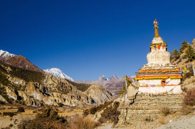 Bhraka (Braga) köyü yakınlarındaki Marshyangdi nehir vadisinde yürüyüş güzergahında beyaz stupa. Annapurna gezisi, Nepal.