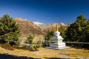 Beyaz stupa, Milarepa 'nın Bhraka (Braga) köyü yakınlarındaki Marshyangdi nehir vadisindeki mağarasına gidiyor. Annapurna gezisi, Nepal.