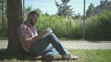 Adam yüksek sesle kitap ağacı, pan atış altında okuma.