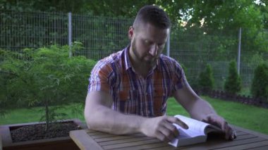 Adam masada oturan ve kitap okuma.