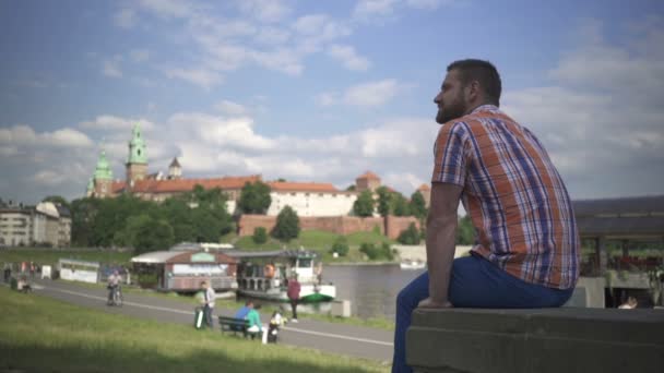 Muž seděl na zdi u řeky — Stock video