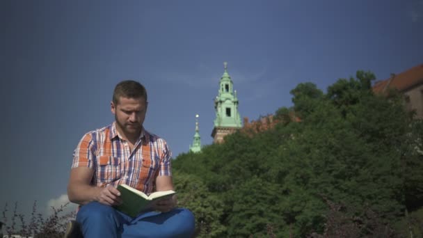 L'uomo smette di leggere il libro e guardarsi intorno . — Video Stock