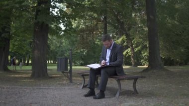 İşadamı parkta bankta oturmuş belgelerle çalışma.