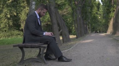 Laptop, Park, pan atış bankta oturmuş çalışma iş adamı.