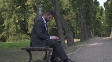 Laptop, Park, bankta oturmuş çalışma işadamı atış eğimli.