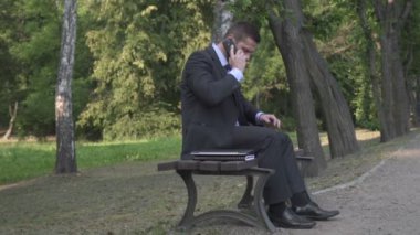 Smartphone ile konuşmak ve dizüstü bilgisayar tarama işadamı.