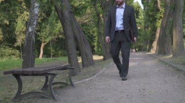 İşadamı parkta bankta oturur ve belgelerle çalışmaya başlar.