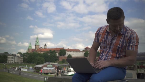 Mann tippt auf Laptop und antwortet auf Smartphone. — Stockvideo