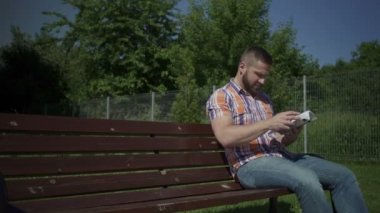 Adam tahta bankta kitap okuyor..