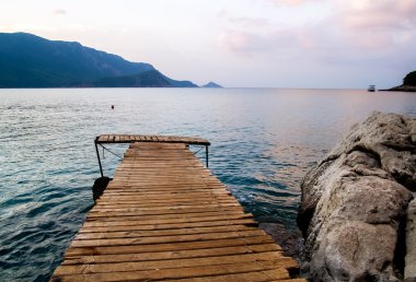 Çıralı plaj üzerinde thatched şemsiye altında güverte sandalyeleri.