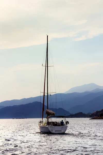 Barca a vela in mare sullo sfondo delle montagne . Immagini Stock Royalty Free