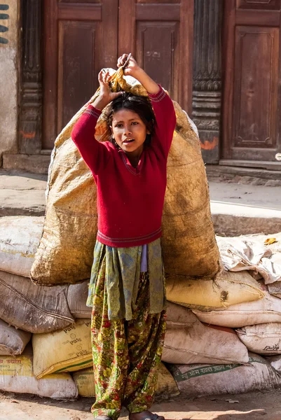 BHAKTAPUR, NEPAL - 19 DE ABRIL DE 2013: Trabajo infantil en Asia. Chica te Imagen de stock