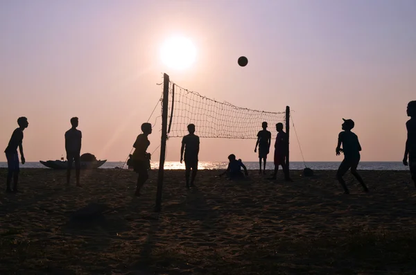 Шри-Ланка, Негомбо, 10 января 2016 - Мальчики играют в волейбол на пляже. Закат. Подсветка Стоковое Изображение
