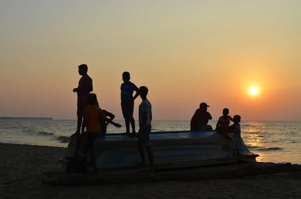 Sri-Lanka, Negombo, 10 января 2016, Backlight Boys on the flipped boat. Подсветка Лицензионные Стоковые Фото