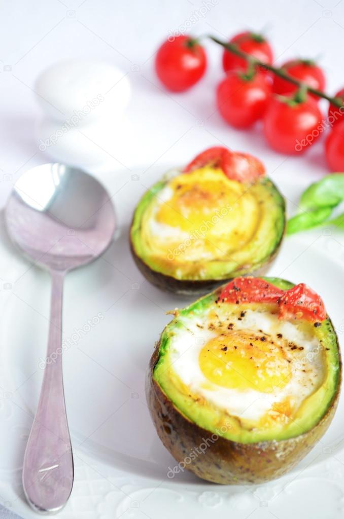 Egg baked in avocado with cherry on the white background