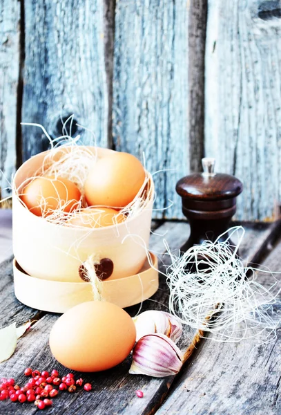 Три яйца в деревянной коробке с красным перцем и перцем на винтажном фоне — стоковое фото