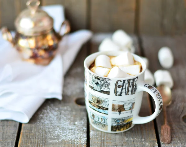 White marshmallow in the cup of coffee on the old wooden background