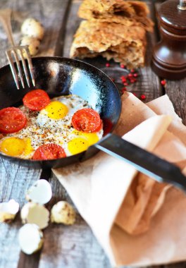 Domates ve fesleğen eski ahşap masa üzerinde siyah tavada omlet