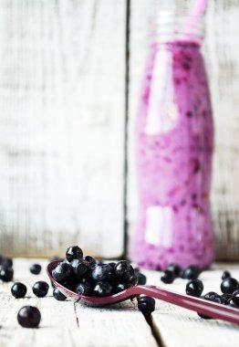 Beyaz ahşap zemin üzerinde şişede Blueberry smoothie
