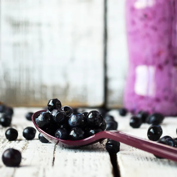 Blueberry smoothie in de fles op de witte achtergrond van hout — Stockfoto