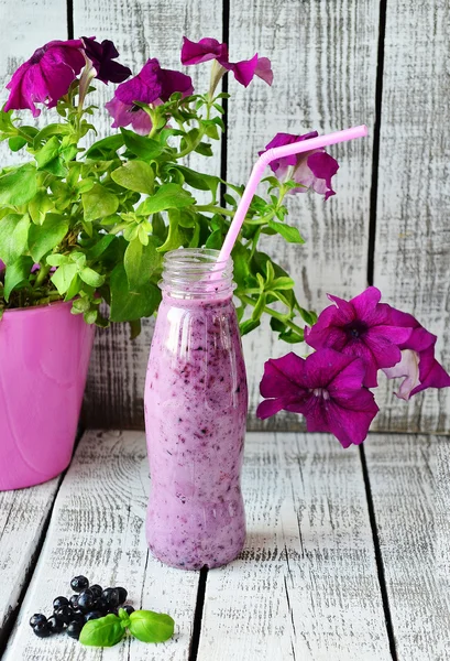 Blueberry smoothie på flaska med rosa pinne på vit trä bakgrund — Stockfoto