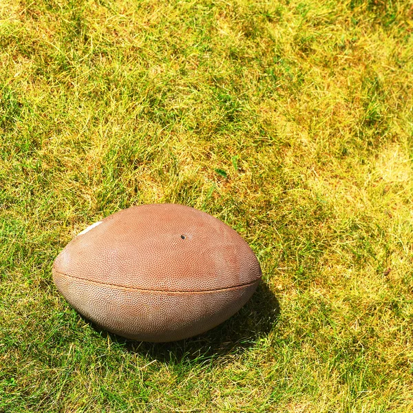 Míč na americký fotbal na žluto zelené trávy — Stock fotografie