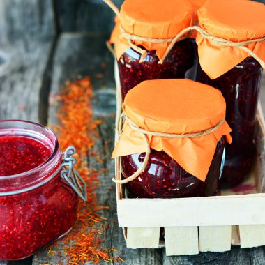 Jars with raspberry jam on the wooden table with spices