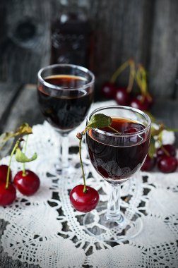 Küçük gözlük ve vintage gelmedi eski ahşap arka plan üzerinde büyük şişe kiraz likörü