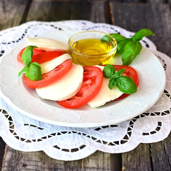 Итальянский салат Caprese с оливковым маслом в маленькой стеклянной миске на белой винтажной салфетке — стоковое фото