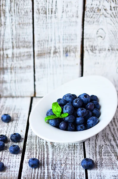 Kom met bosbessen op de witte houten tafel met basilicum blad wit — Stockfoto