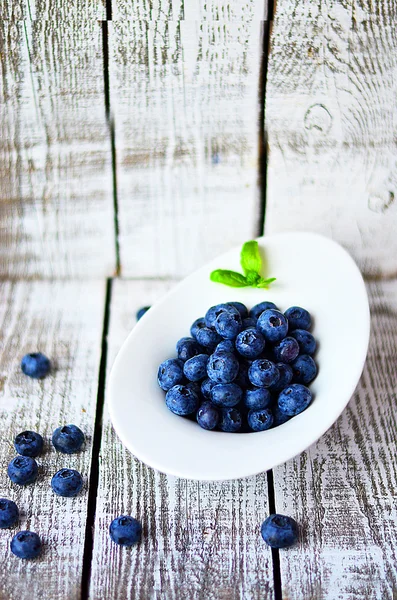 White bowl  with blueberries on the white wooden table with basil leaf — Stock Photo, Image