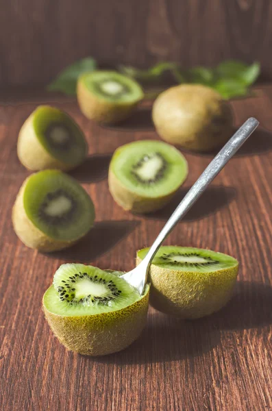 Frutas de kiwi inteiras e fatiadas em uma mesa marrom de madeira, foco seletivo — Fotografia de Stock