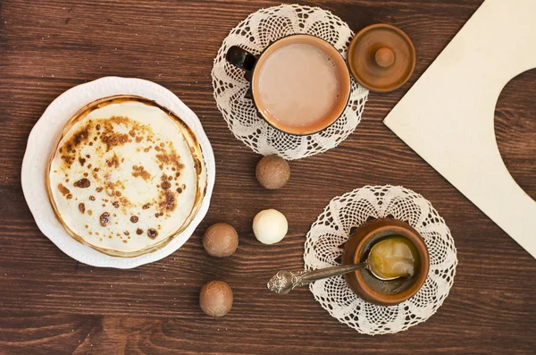 Блинчики с сахарным порошком и медом и чашкой кофе на винтажной салфетке на коричневом деревянном фоне, завтрак, шоколадные конфеты. Рамка для фотографий. Тонированная картинка, избирательный фокус — стоковое фото
