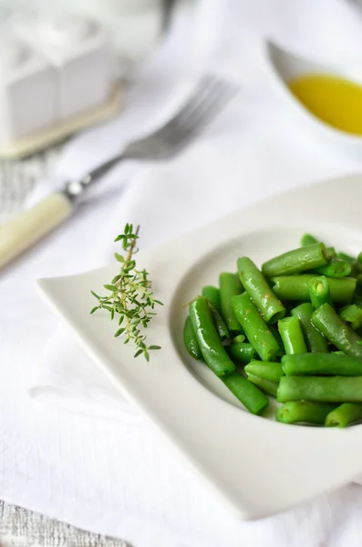 Cooked green beans with olive oil on the white plate