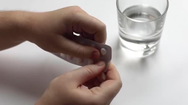 Mani umane estrarre una pillola dalla confezione e prendere un bicchiere d'acqua pulita, prendere medicine, primo piano — Video Stock