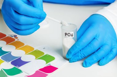 Tıbbi eldivenli laboratuvar asistanı elinde akvaryum suyunu test etmek için bir reaktör tutuyor, yakın plan.