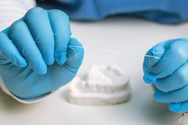 dentist holding dental floss against white desktop background, oral hygiene products