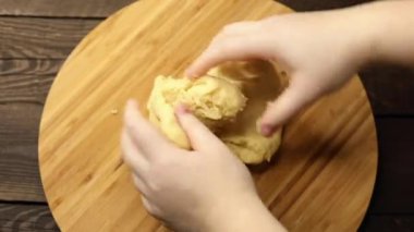 Yemek hazırlama süreci, kadın hamuru ahşap bir masaya yoğurur, elleri yakın, pişirme hazırlığı